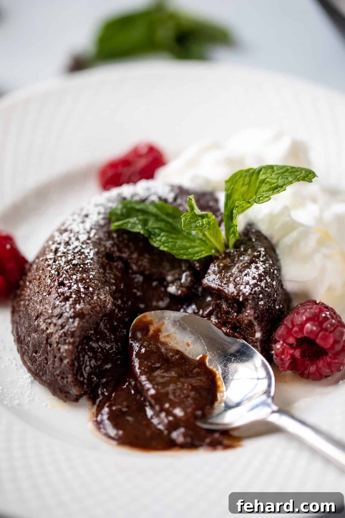 Instant Pot Lava Cake Chocolate lava cake on white plate with spoon cutting into it to show chocolate ooze.
