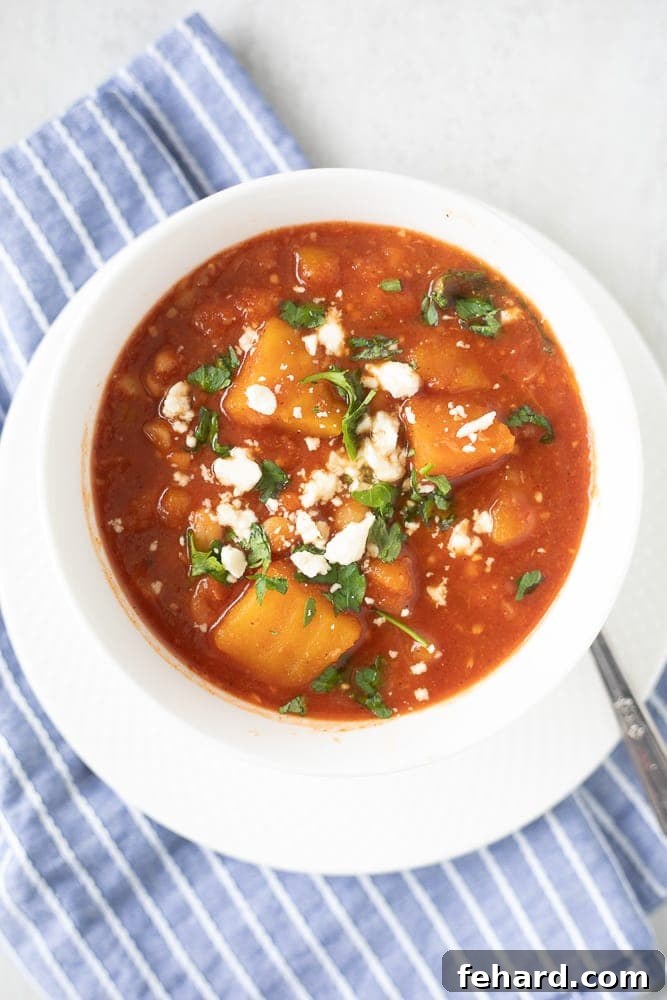 White bowl filled with rich Butternut Squash Chili, garnished with fresh cilantro, ready to be enjoyed.