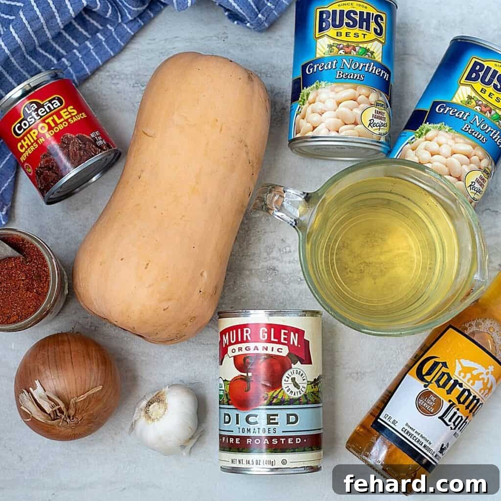 Selection of fresh ingredients for Butternut Squash Chili laid out on a kitchen counter, including cubed squash, onions, garlic, canned goods, and spices.