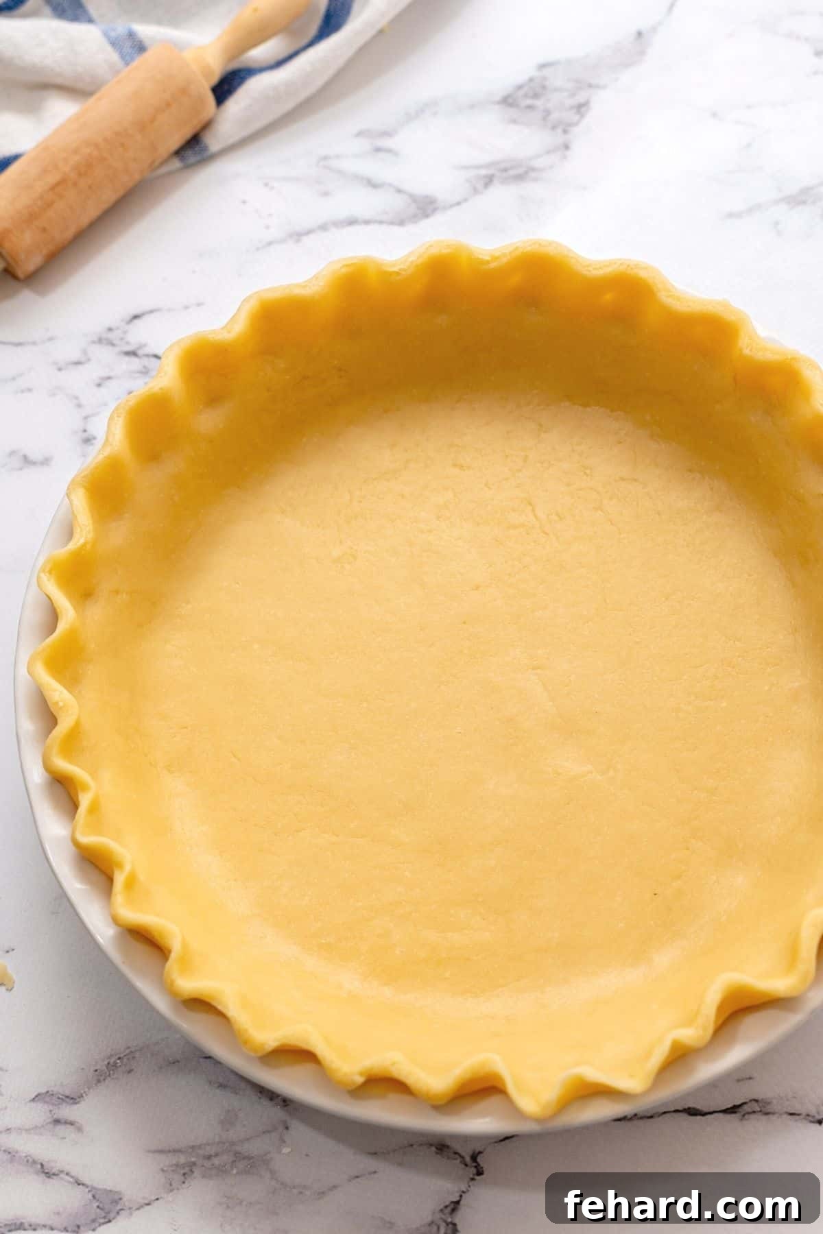 Beautifully fluted pie crust in a ceramic pie plate, showcasing its tender, golden-brown edges ready for filling. This image highlights the perfect texture and appearance of a homemade all-butter pie crust.