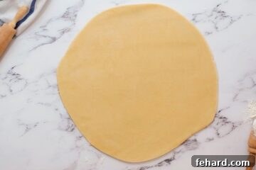 Pie dough rolled out into a smooth, even 12-inch circle on a lightly floured work surface, ready for transfer to the pie pan.