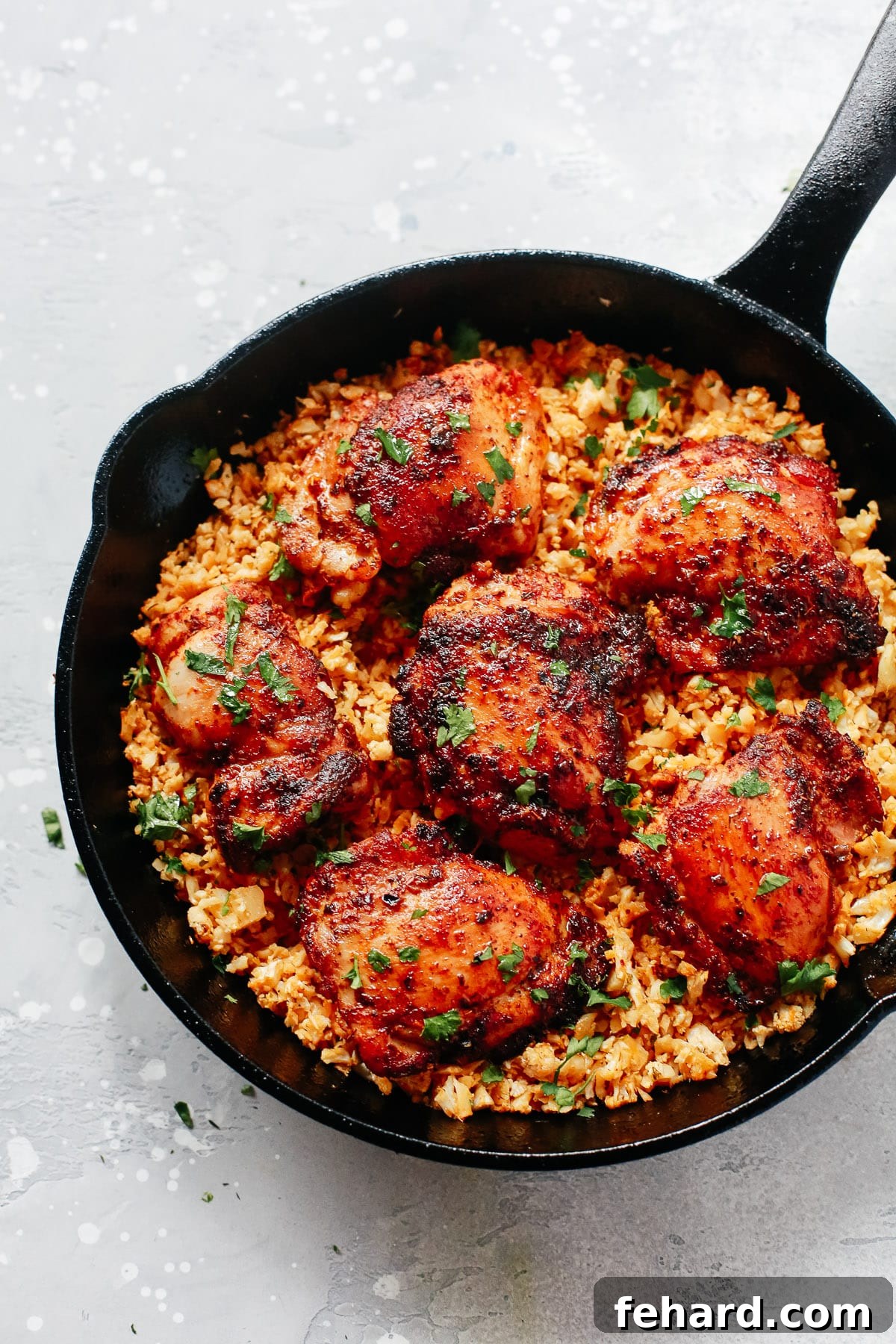 Close-up of a cast iron skillet filled with spicy chicken and fluffy cauliflower rice, a low-carb and flavorful meal.