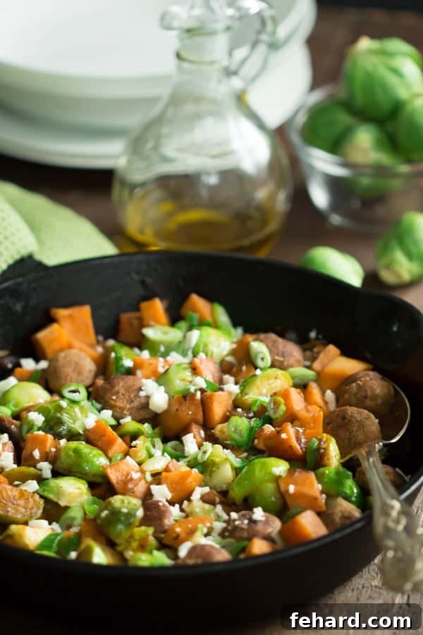 Close-up of a cast iron skillet showcasing savory turkey sausage with roasted Brussels sprouts and sweet potatoes.