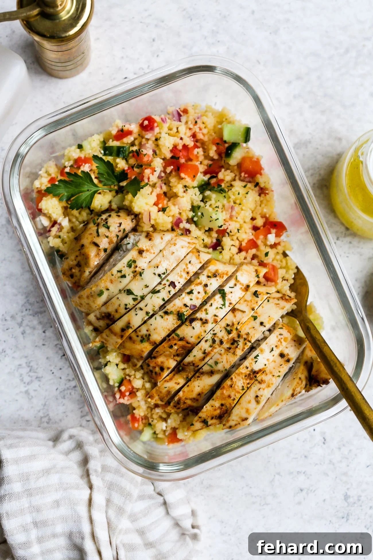 Chicken couscous salad in a small, glass meal-prep container.