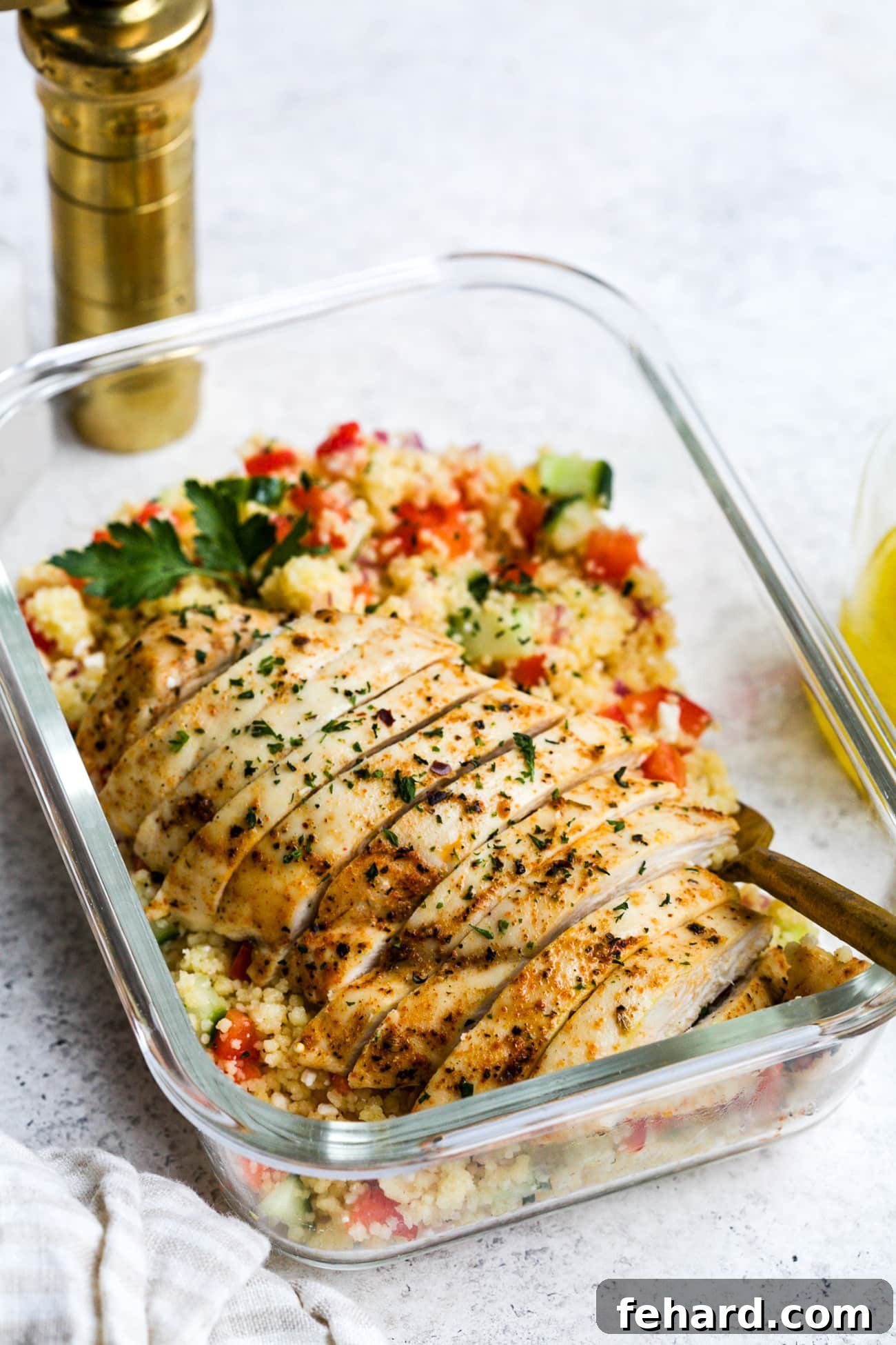 Chicken couscous salad in a small, glass meal-prep container.