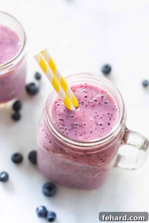 Emerald Mango Delight 3 Delicious Blueberry Banana Smoothie served in a glass, topped with fresh blueberries.