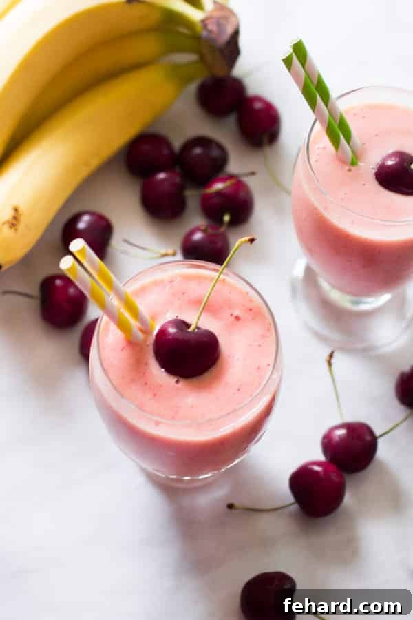 Emerald Mango Delight 4 Overhead photo of two glasses of vibrant cherry pineapple smoothies, garnished with fresh cherries.
