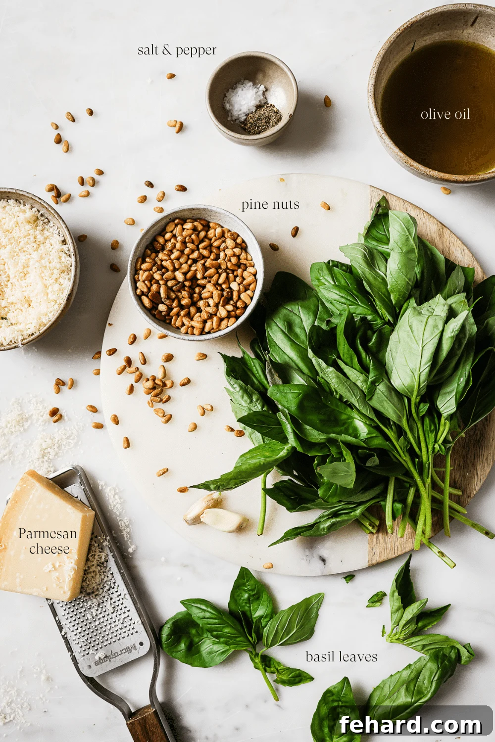 Pre-measured fresh ingredients for basil pesto on a clean white countertop, arranged artfully before blending.