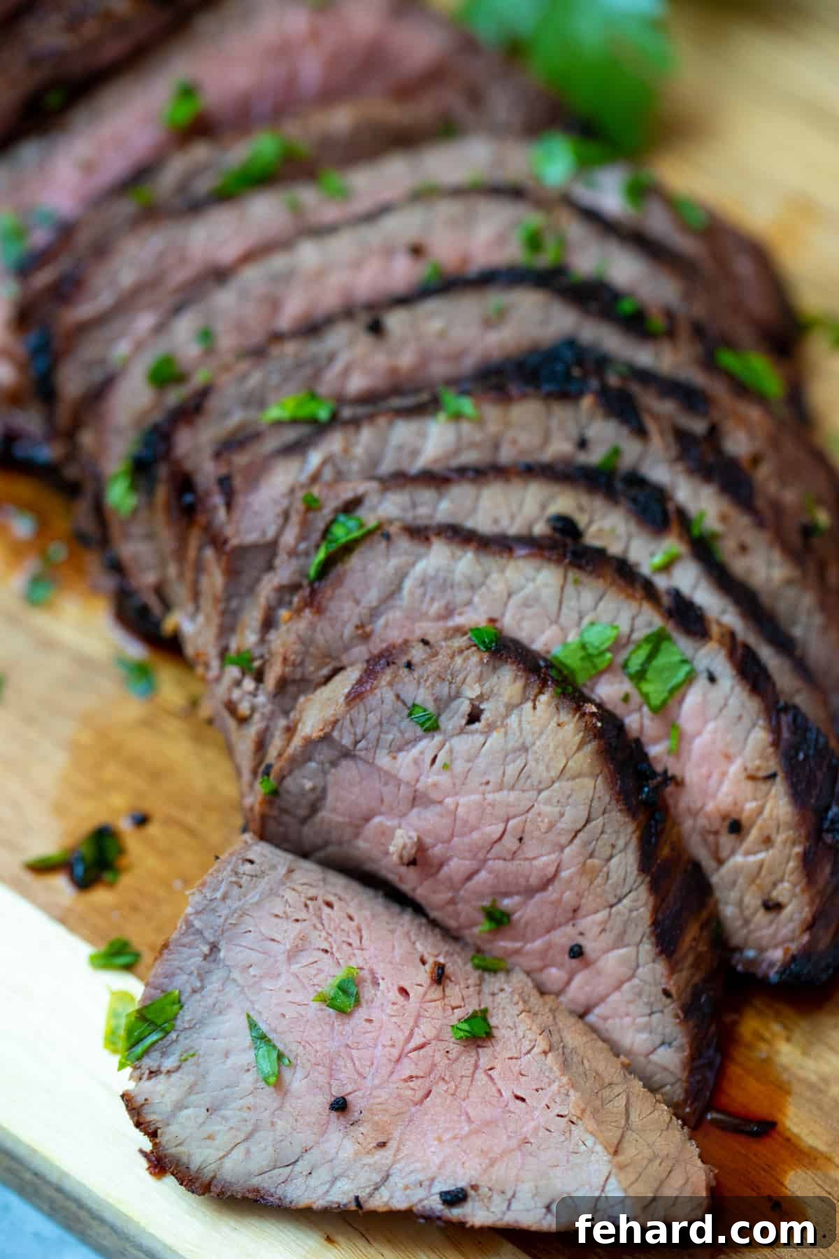 London Broil Perfectly sliced London Broil arranged on a wooden cutting board, ready to serve.
