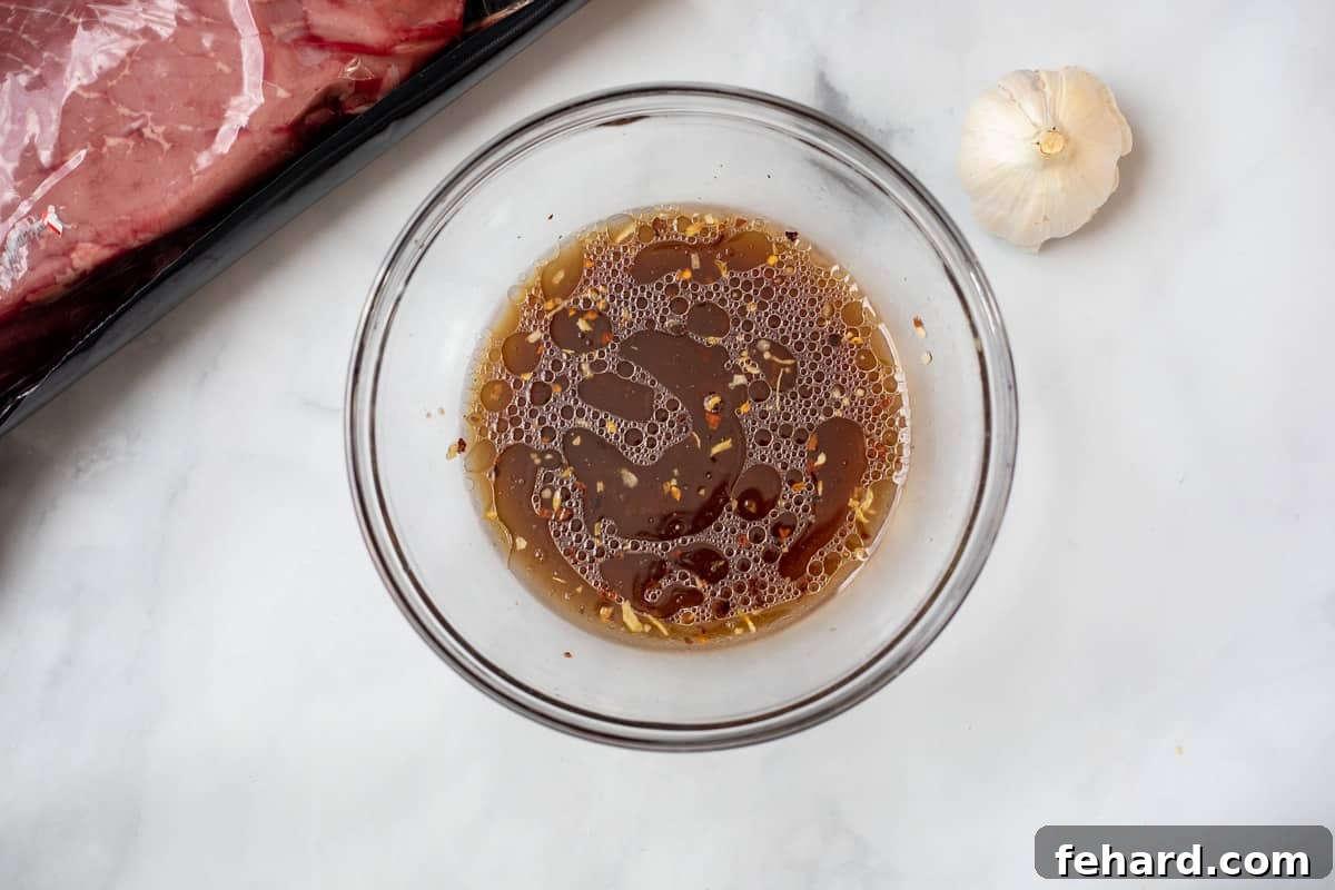 London Broil Recipe A small mixing bowl filled with whisked London Broil marinade, showcasing its rich color and consistency.