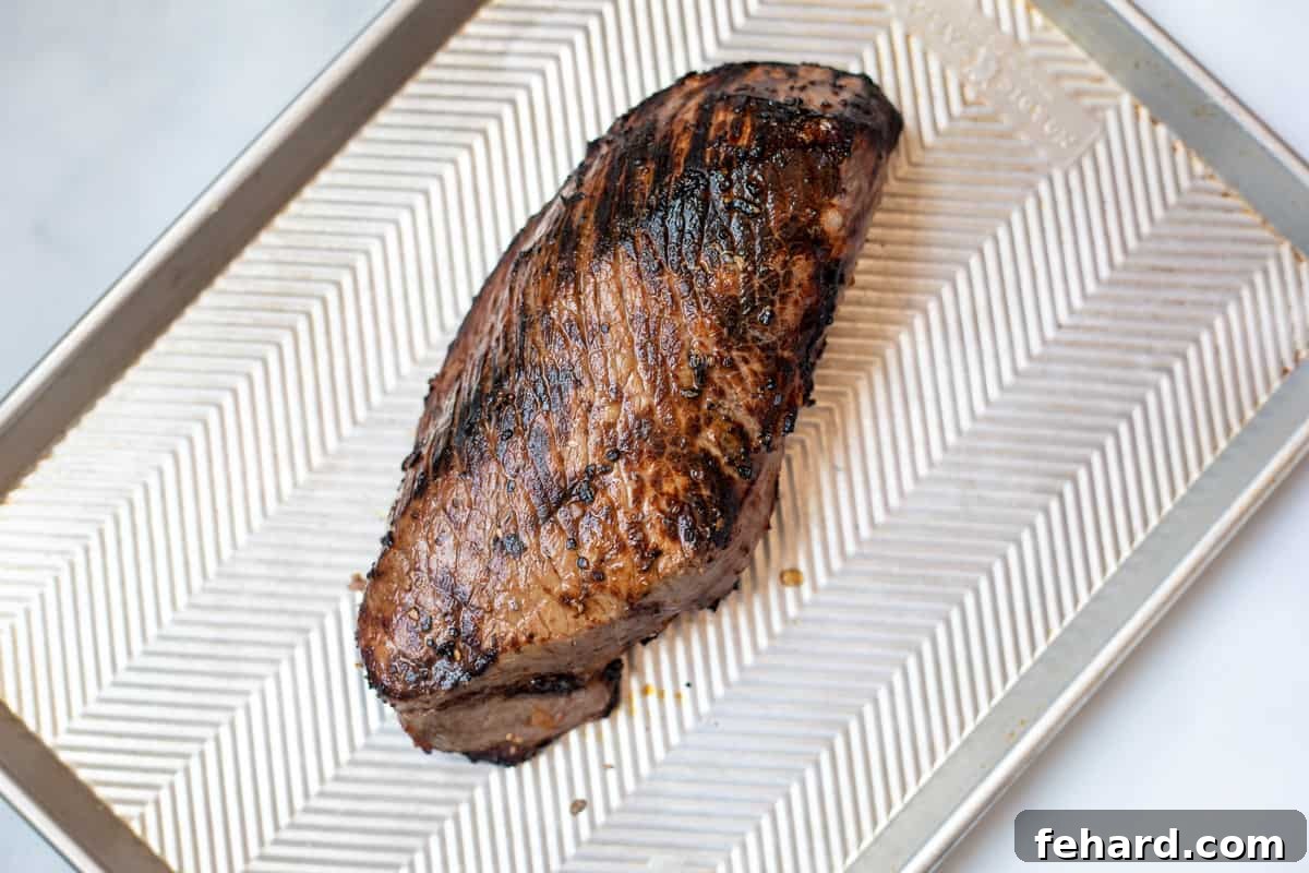 Recipe London Broil A freshly broiled London Broil resting on a sheet pan, showcasing a beautiful caramelized crust.
