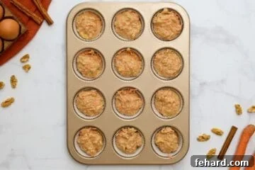 Carrot cake muffin batter divided up between 12-cup muffin tin.