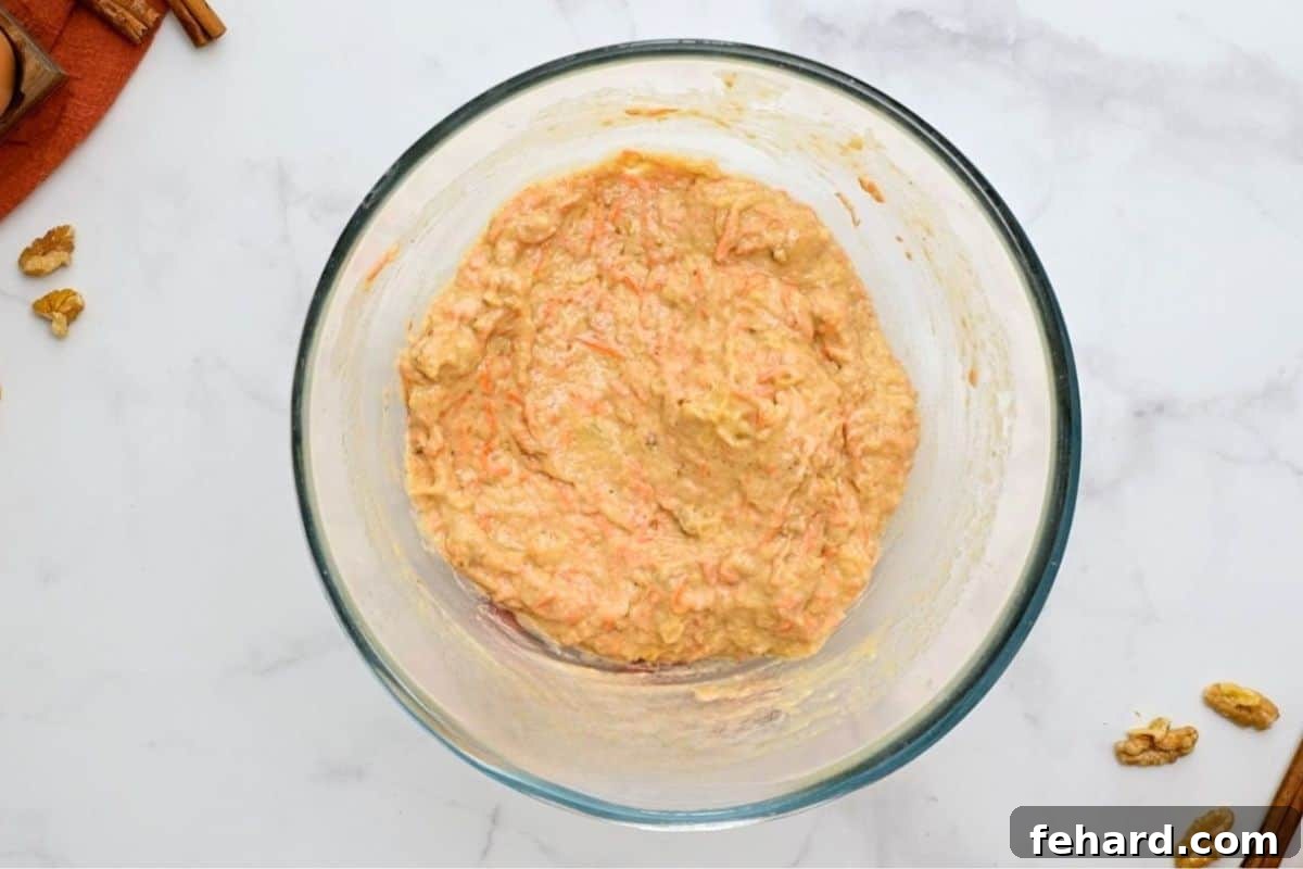 Carrot Cake Batter in a clear mixing bowl, showing its thick consistency.