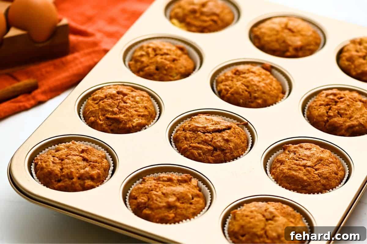 12 freshly baked carrot cake muffins in a muffin tin.