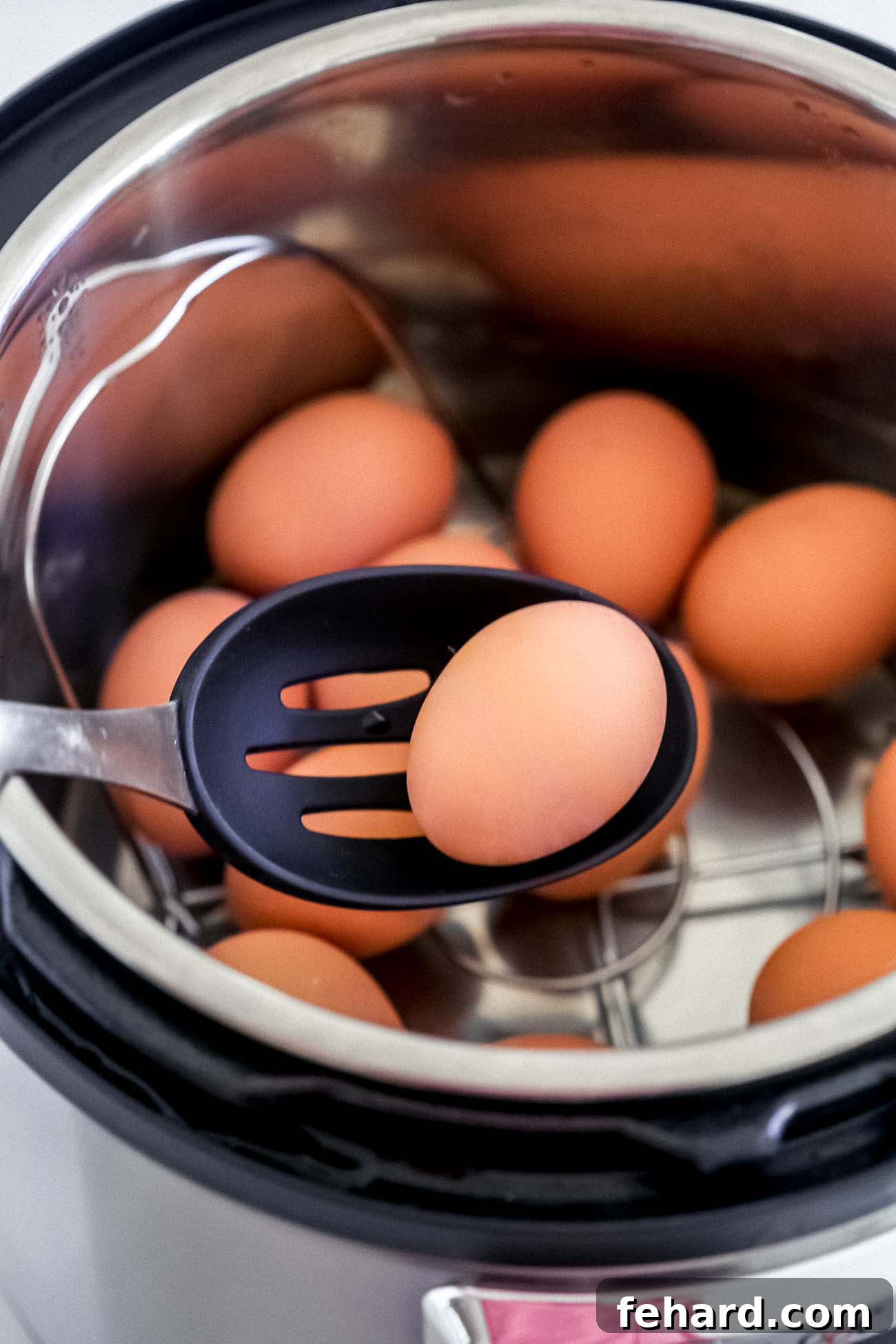 Hard boiled eggs being carefully transferred from the Instant Pot to an ice bath.