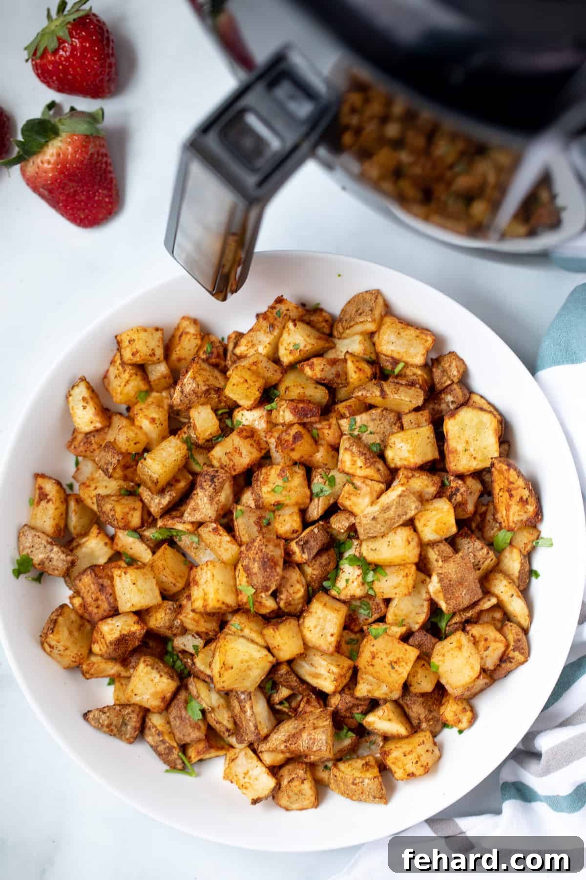 Crispy Air Fryer Potatoes: Golden and Delicious A bowl overflowing with golden, crispy air fryer potato cubes, positioned next to a sleek air fryer appliance.