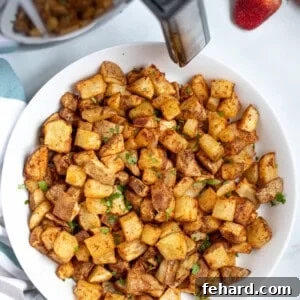 Bowl of Crispy potatoes next to air fryer.