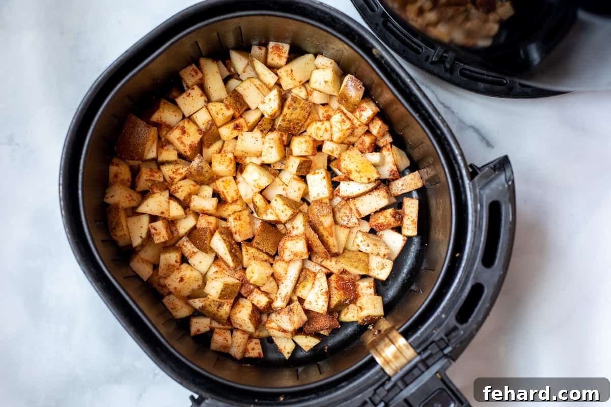 Air Fryer Potato Setup Seasoned, cubed potatoes spread out evenly in a single layer within an air fryer basket, ready for cooking.