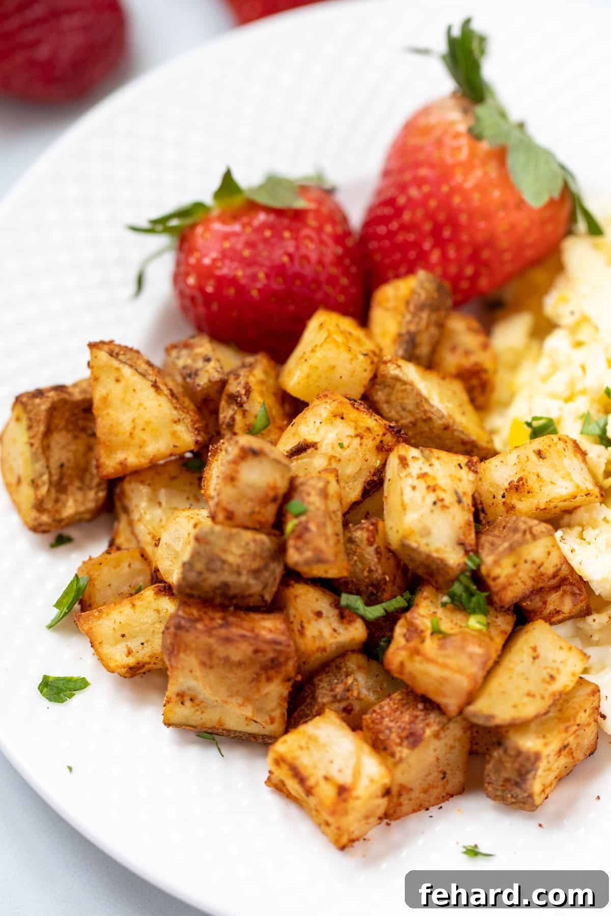 Air Fryer Hash Browns for Breakfast A white plate featuring a generous serving of crispy air fryer hashbrown potatoes next to a portion of scrambled eggs, creating a classic breakfast combination.