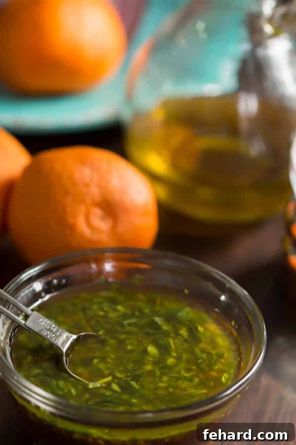 Fresh Clementine Salad Dressing in a glass jar, ready to be drizzled over a vibrant green salad, showcasing its bright orange hue and the delicate zest.