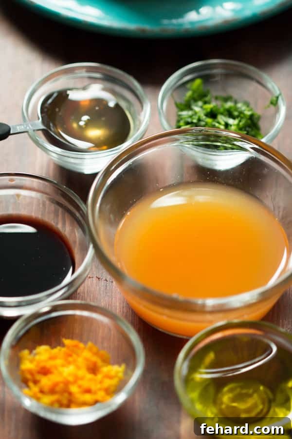 A close-up of a small glass bowl filled with the freshly made Clementine Salad Dressing, a whisk resting beside it, highlighting its smooth texture and rich color.