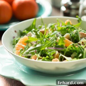 Finished Clementine Arugula Salad, beautifully plated and ready to be served, garnished with cashew nuts and feta cheese.