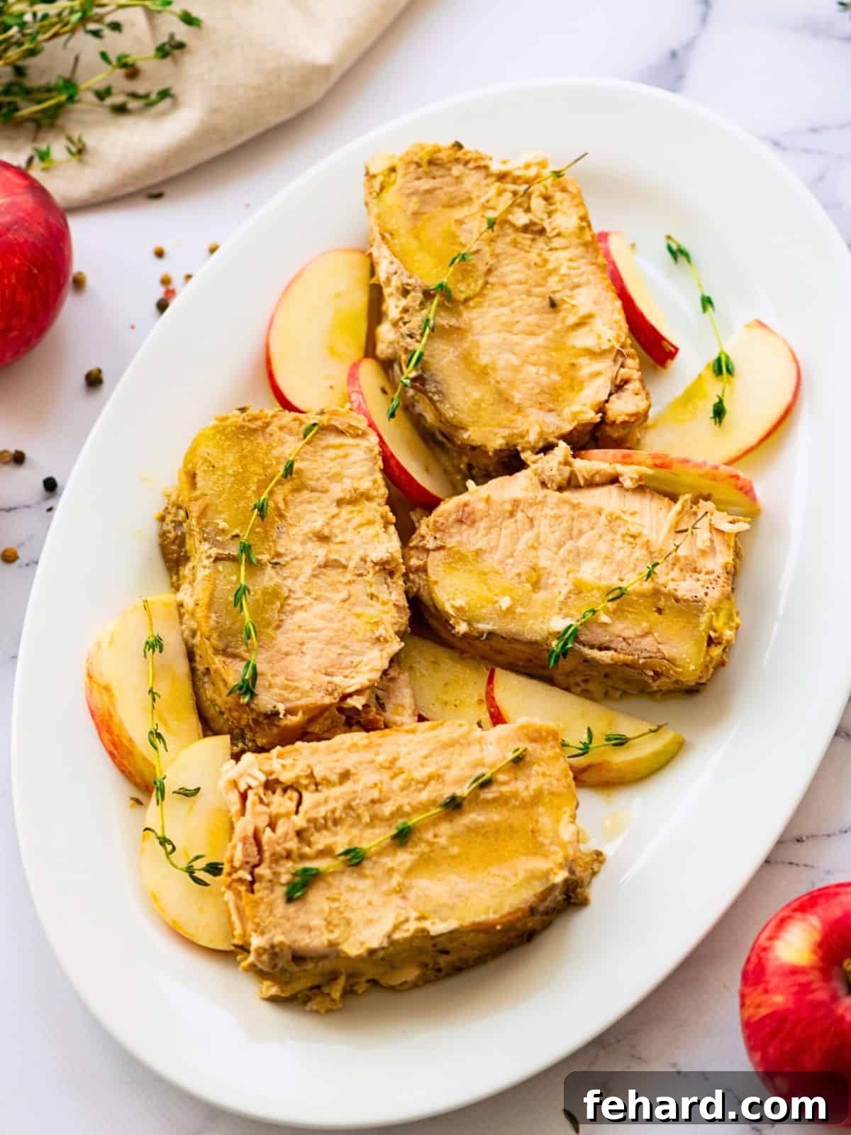 Pork loin sliced on white platter after being slow cooked with apples and onions.
