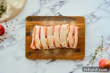 Pork roast with slits cut into top and apples inserted into slits.
