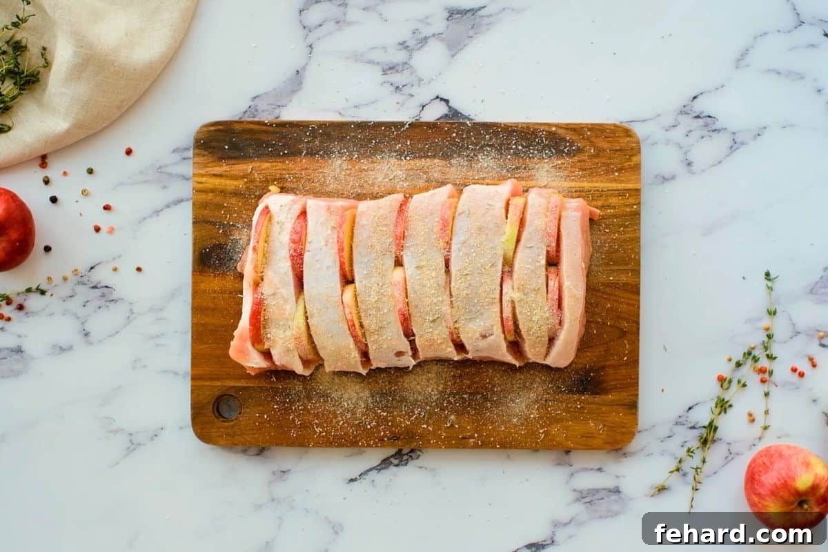 Pork roast with slits cut into top and apples inserted into slits.
