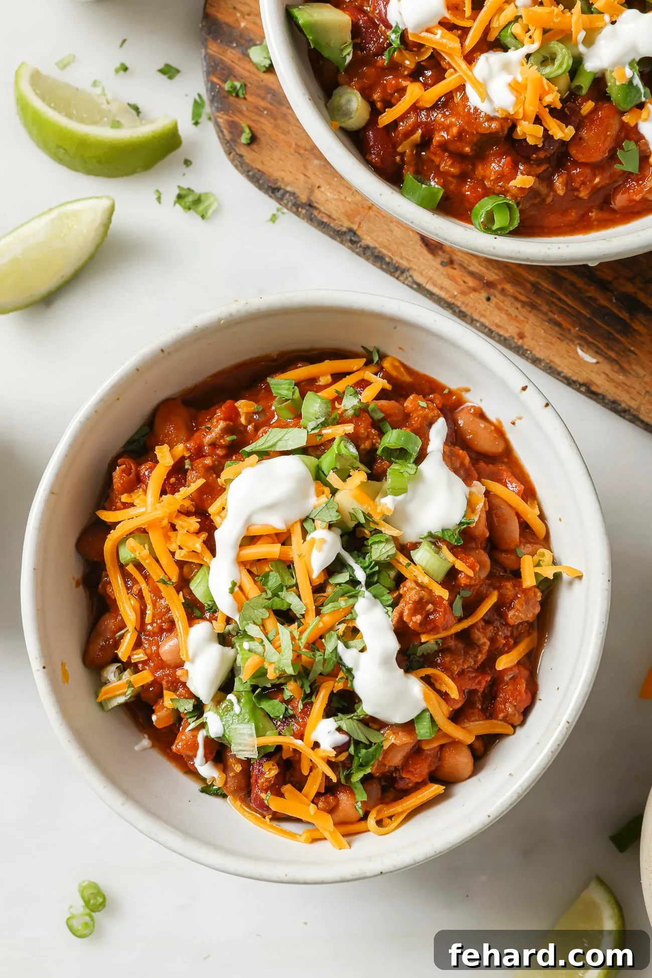 Set It and Forget It Chili 2 Slow cooker chili in a bowl with vibrant toppings like green onions, cilantro, sour cream, and avocado, ready to be enjoyed.