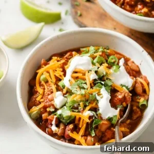 Set It and Forget It Chili 10 A vibrant and appetizing image of slow cooker chili, served in a bowl with fresh, colorful toppings.