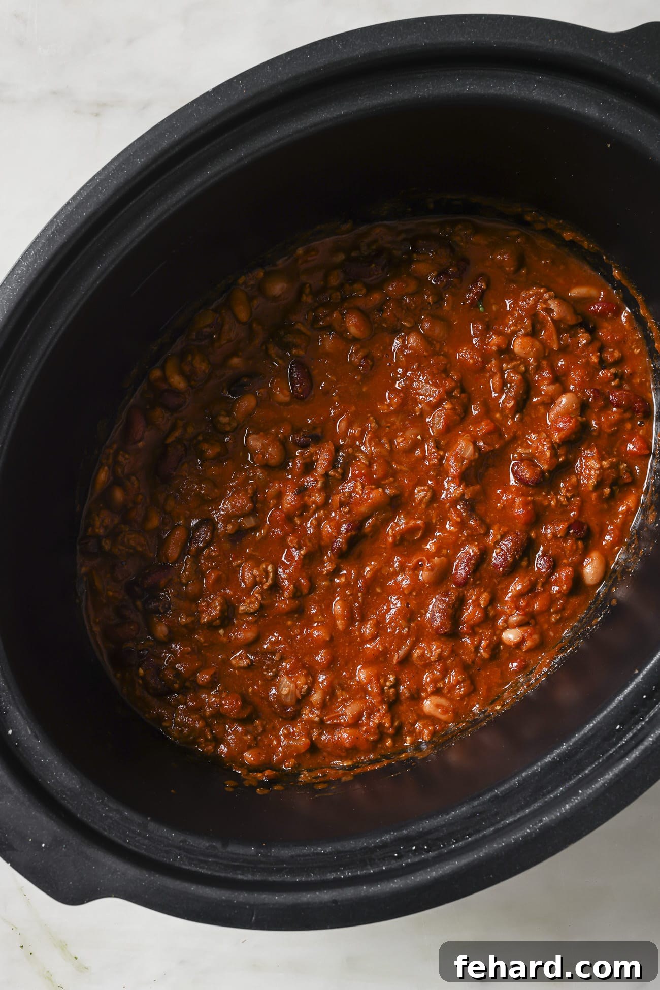 Set It and Forget It Chili 7 A close-up view of the rich, simmering chili inside a slow cooker, showcasing its texture and deep color.