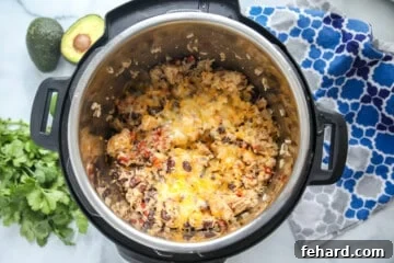 Effortless Instant Pot Burrito Bowls 9 Chicken and rice covered in cheese inside inner pot of instant pot.