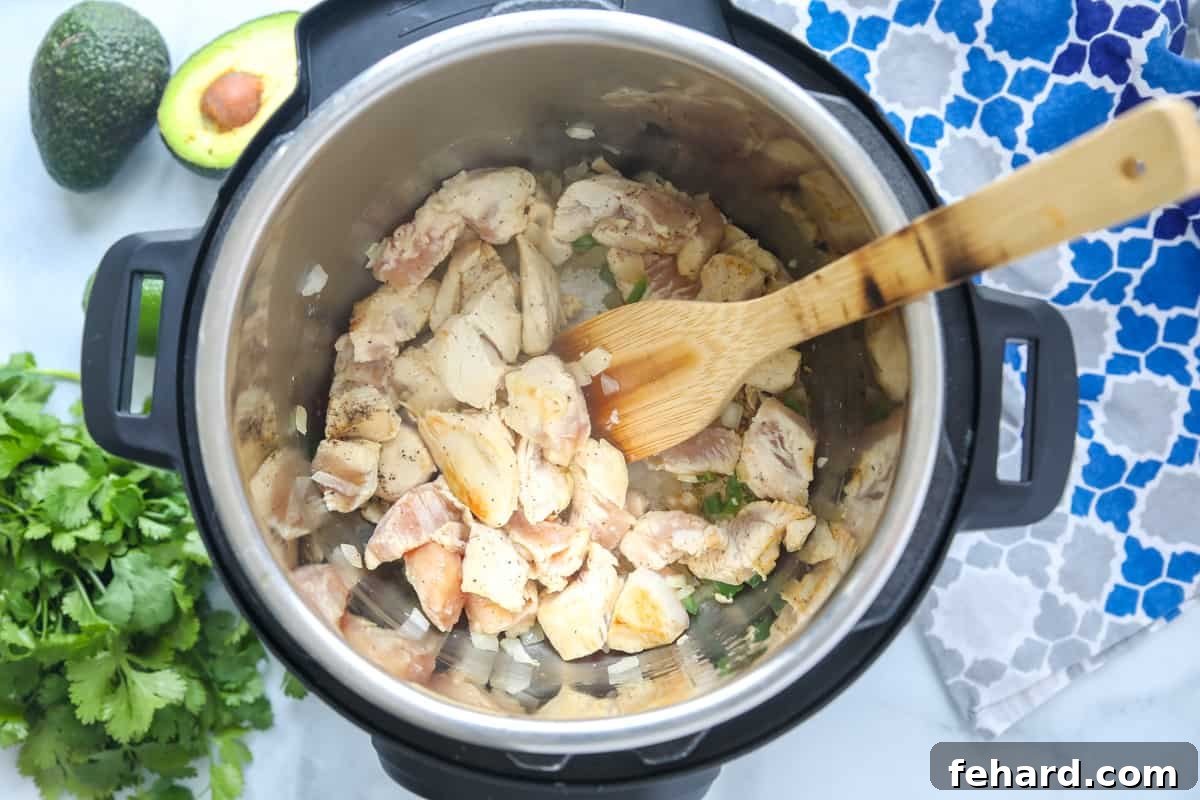 Instant Pot Chicken Burrito Bowl Browning Cubed chicken browning in the inner pot of an Instant Pot.