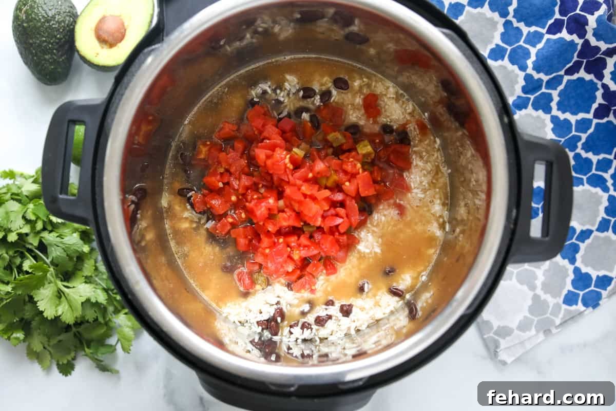 Healthy Instant Pot Burrito Bowl Prep Rotel tomatoes topping rice, beans, and chicken in the Instant Pot.