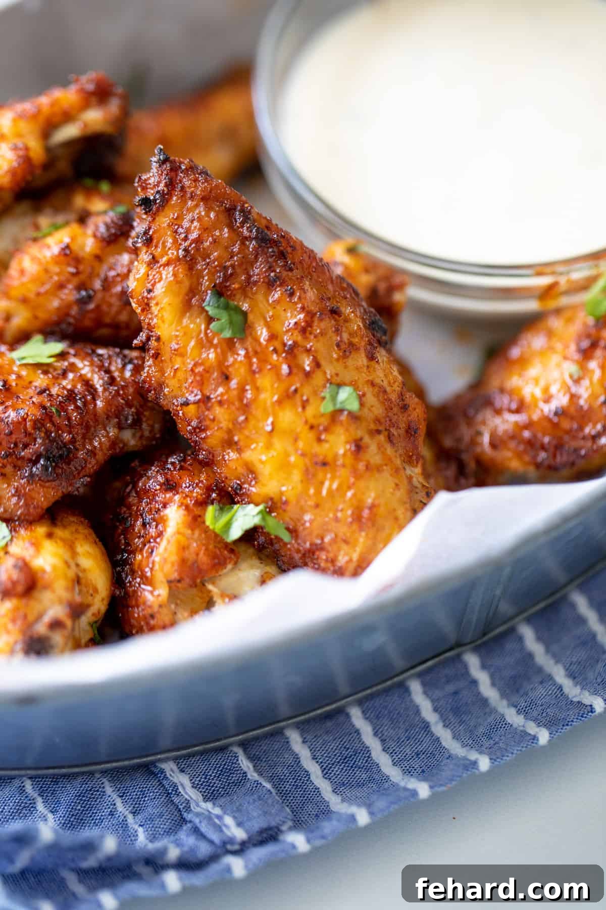 Best Air Fryer Chicken Wings Recipe Close up of dry rubbed air fryer wings in a silver basket, showcasing their perfectly crispy skin and golden-brown hue.