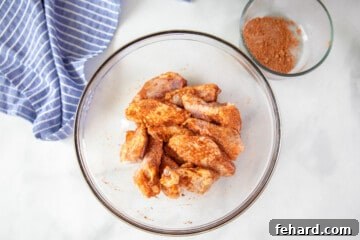 Chicken wings, coated with dry rub and oil, glistening in a clear mixing bowl, poised for air frying.