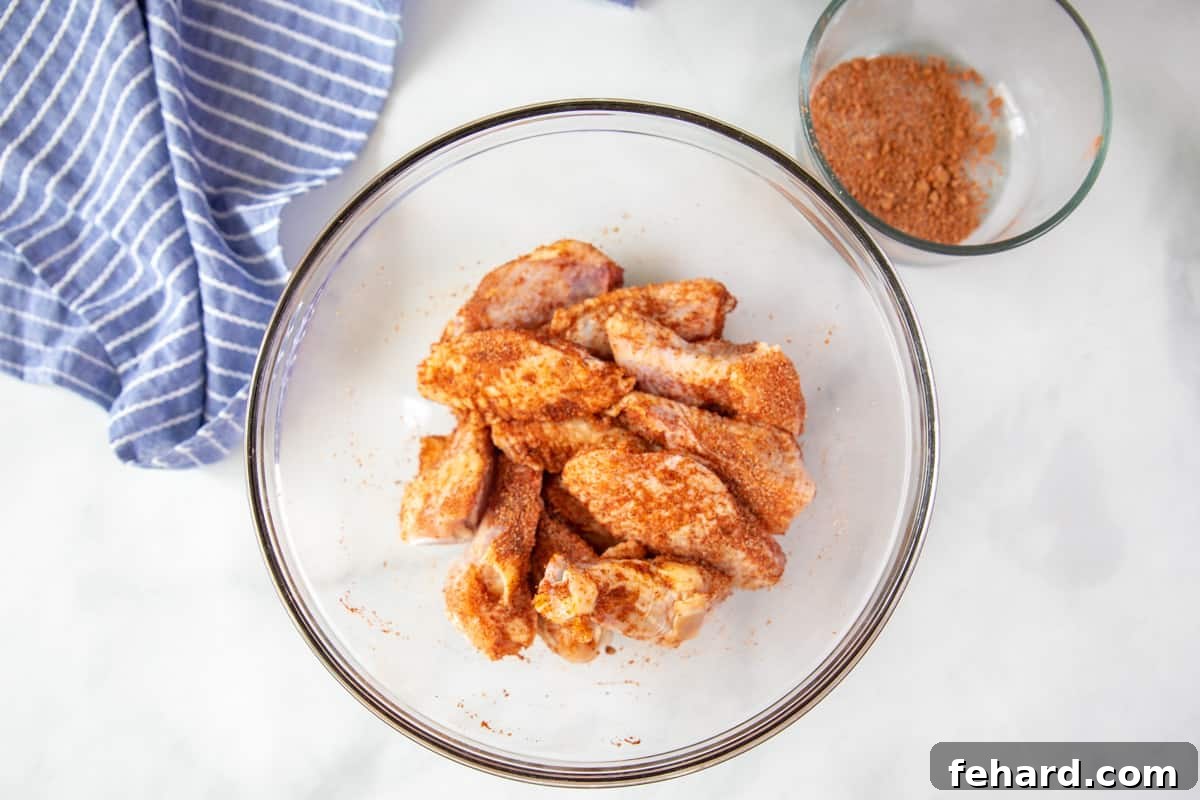 Air Fryer Chicken Wings with Dry Rub Chicken wings expertly tossed with a flavorful dry rub and oil in a clear mixing bowl, ready for air frying.
