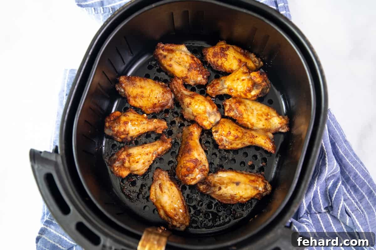 Chicken Wings Air Fryer Recipe Crispy chicken wings perfectly cooked and arranged in an air fryer basket, ready to be removed.