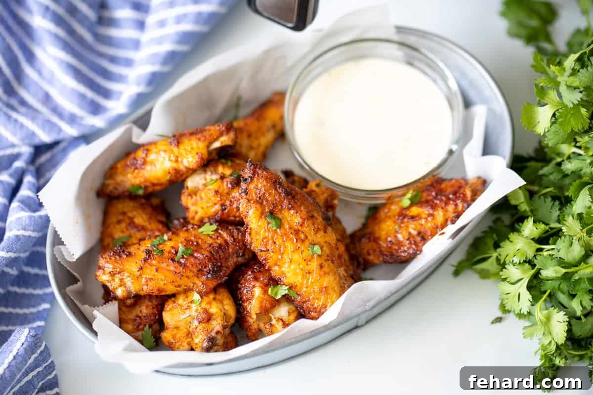 Chicken Wings Air Fryer A basket brimming with golden-brown Air Fryer Chicken Wings, placed invitingly next to an air fryer on a clean counter.