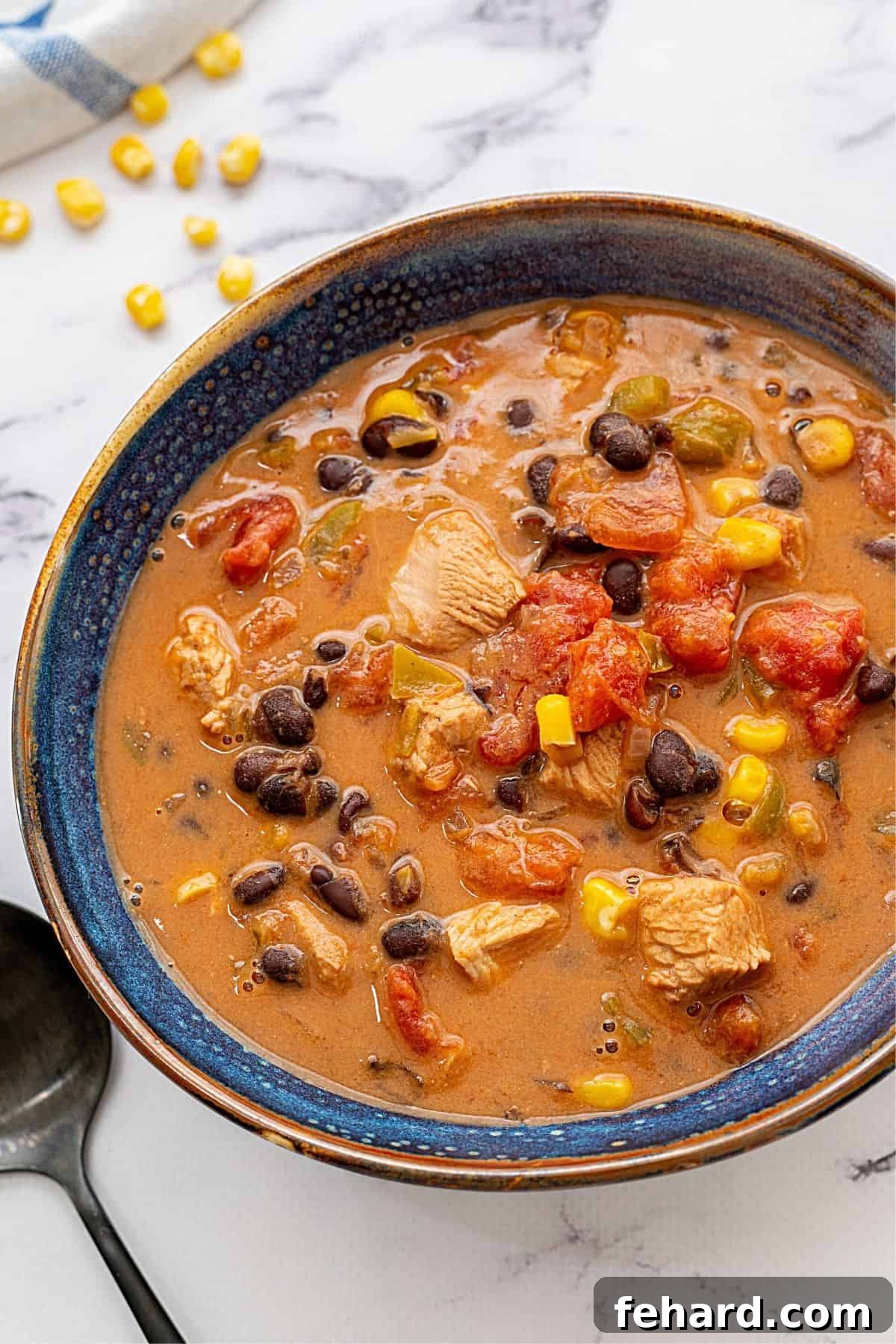 Creamy Southwest Leftover Turkey Soup A bowl filled with a creamy Southwest Turkey Soup, featuring visible chunks of tender turkey, bright yellow corn, and dark black beans, garnished with fresh cilantro.