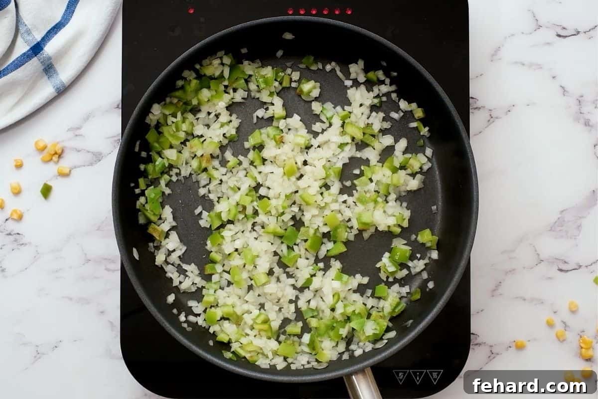 Sautéed Vegetables for Leftover Turkey Soup Diced onions and green bell peppers sautéing in a skillet, turning translucent and slightly golden, forming the aromatic base for the turkey soup.