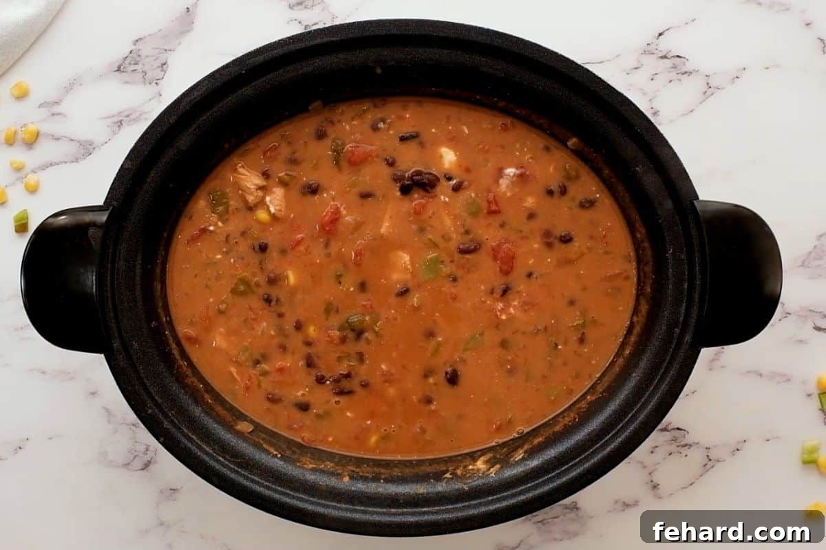 Creamy Turkey Tortilla Soup Recipe The Southwest Turkey Soup in a slow cooker after adding cream cheese, showing a rich, creamy texture and vibrant ingredients.
