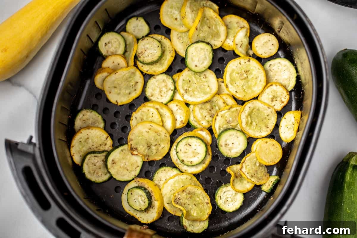 Air Fryer Squash Recipe Sliced zucchini and yellow summer squash seasoned and ready to be air-fried to golden perfection.