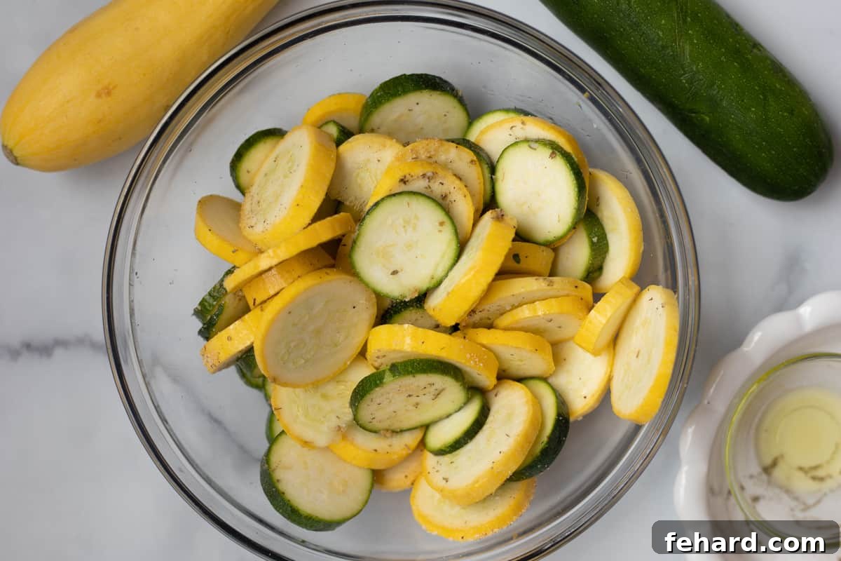 Summer Squash Air Fryer Preparation Sliced squash in a bowl, coated with oil and seasonings, ready for the air fryer.