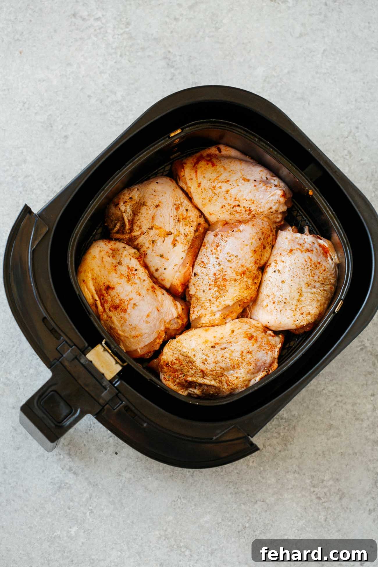 Crispy Air Fryer Chicken Thighs 6 Overhead view of raw, seasoned chicken thighs neatly arranged in a single layer within an air fryer basket, ready for cooking.
