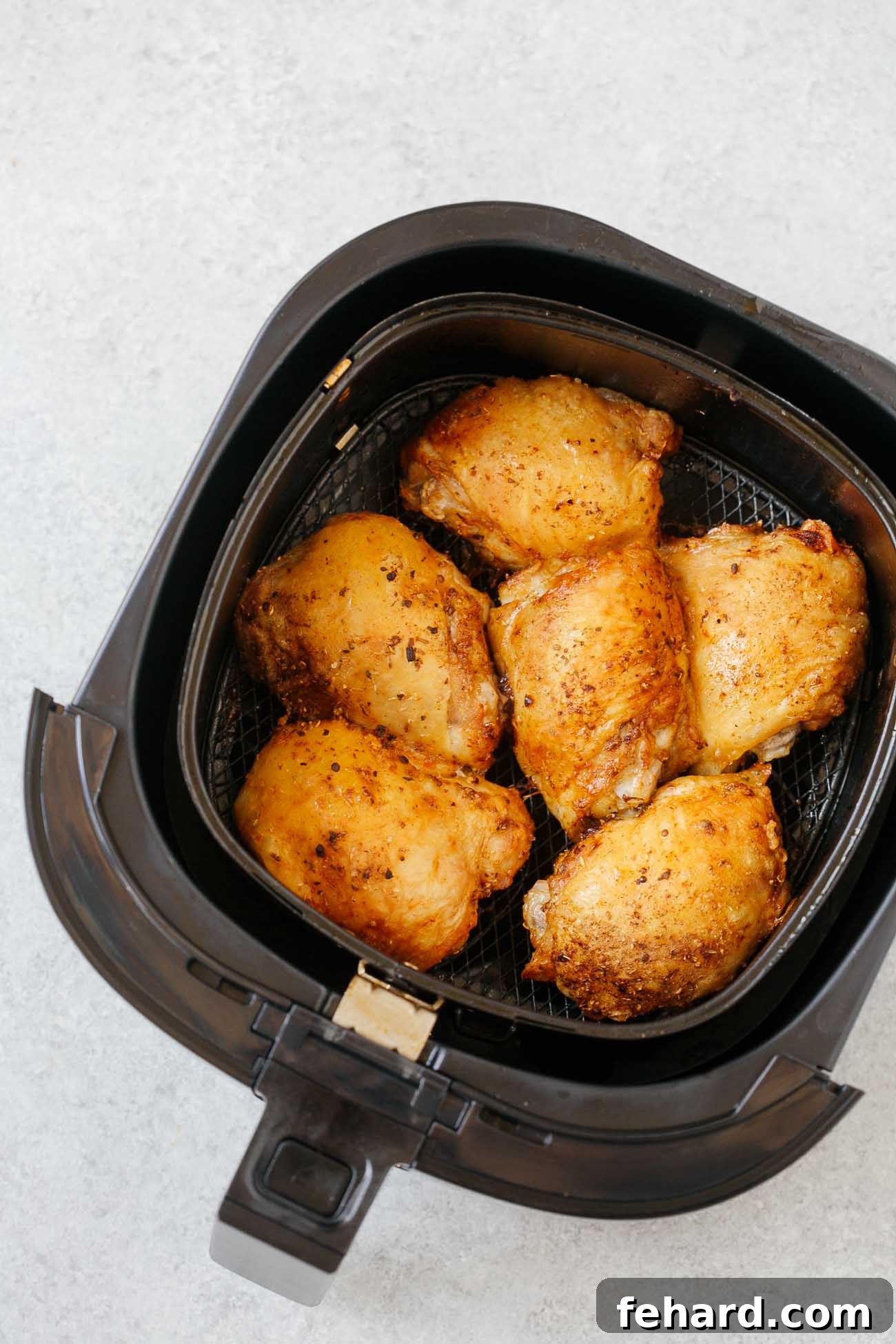 Crispy Air Fryer Chicken Thighs 7 Overhead view of perfectly cooked air fryer chicken thighs, golden-brown and crispy, nestled in the air fryer basket after cooking.