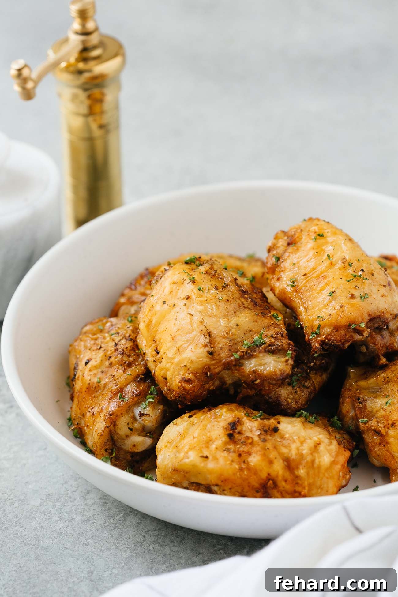Crispy Air Fryer Chicken Thighs 8 A pristine white bowl filled with perfectly golden and crispy air fryer chicken thighs, ready to be served.