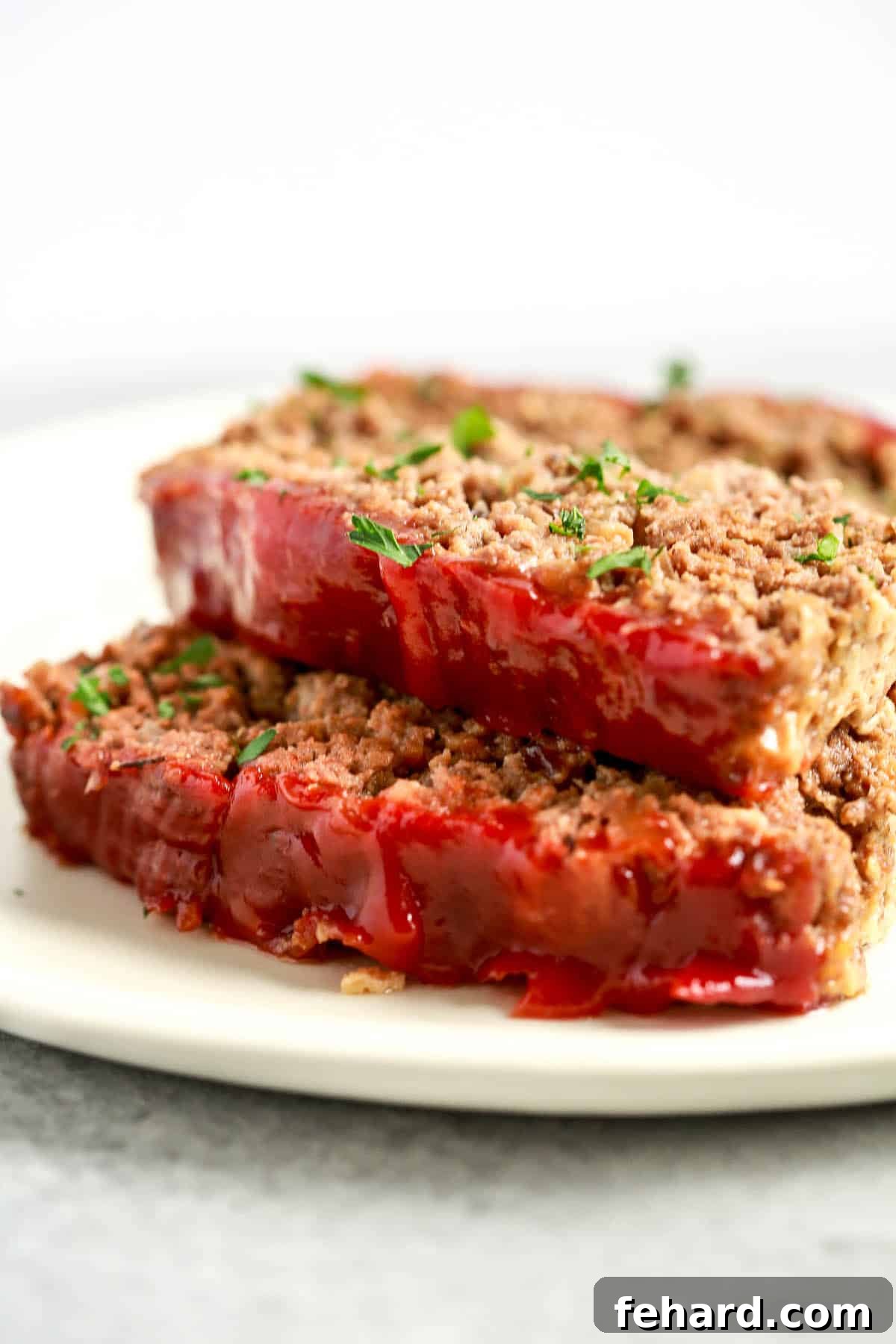 Guilt Free Meatloaf Perfection 8 close up image: two slices of healthy meatloaf with tomato sauce on top