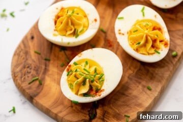 Irresistible Deviled Eggs 8 Three deviled eggs on wooden platter.